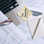 Mesa de trabalho com laptop, documentos e anotação sobre prazo tributário para organização financeira.