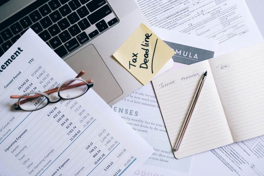 Mesa de trabalho com laptop, documentos e anotação sobre prazo tributário para organização financeira.