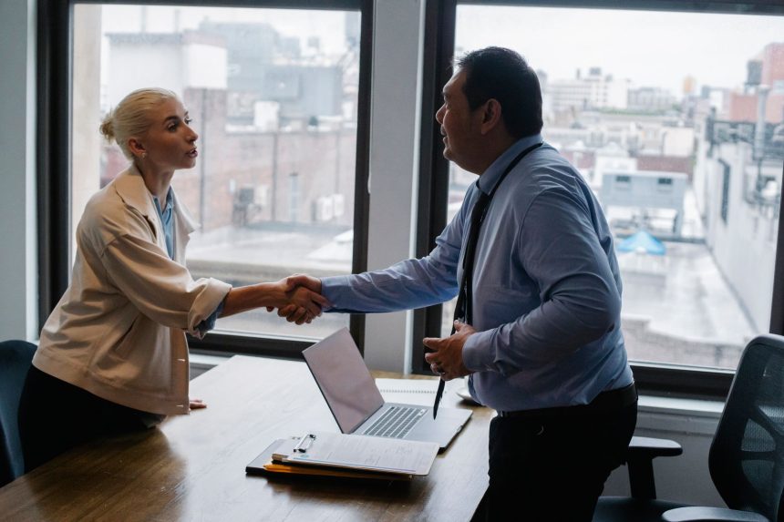 Candidata aperta a mão de um empregador durante uma entrevista de emprego em um escritório.