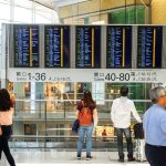Passageiros consultam o painel de partidas no saguão de um aeroporto.