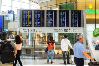 Passageiros consultam o painel de partidas no saguão de um aeroporto.