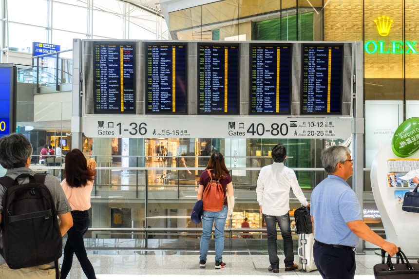 Passageiros consultam o painel de partidas no saguão de um aeroporto.