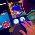 Mão interagindo com botões de uma interface digital colorida de máquina caça-níquel.