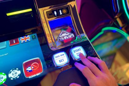 Mão interagindo com botões de uma interface digital colorida de máquina caça-níquel.