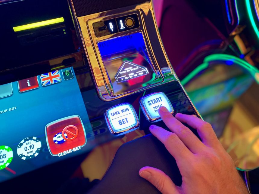 Mão interagindo com botões de uma interface digital colorida de máquina caça-níquel.