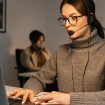 Profissional usando headset enquanto trabalha em um computador em um ambiente de atendimento ao cliente.