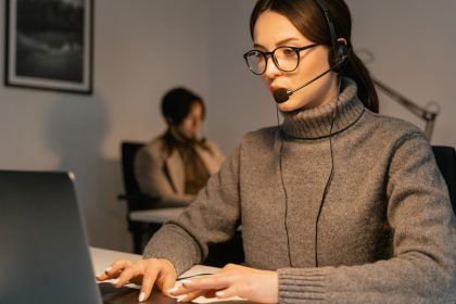 Profissional usando headset enquanto trabalha em um computador em um ambiente de atendimento ao cliente.