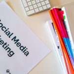 Texto sobre marketing em redes sociais ao lado de livros de design gráfico e um teclado.