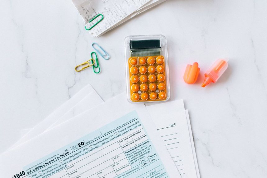 Formulários financeiros, calculadora e materiais de escritório organizados sobre uma mesa.