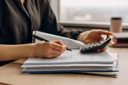 Pessoa usando uma calculadora sobre documentos financeiros em um escritório.