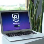 Laptop exibindo uma interface de conexão com blockchain sobre uma mesa, em ambiente interno.
