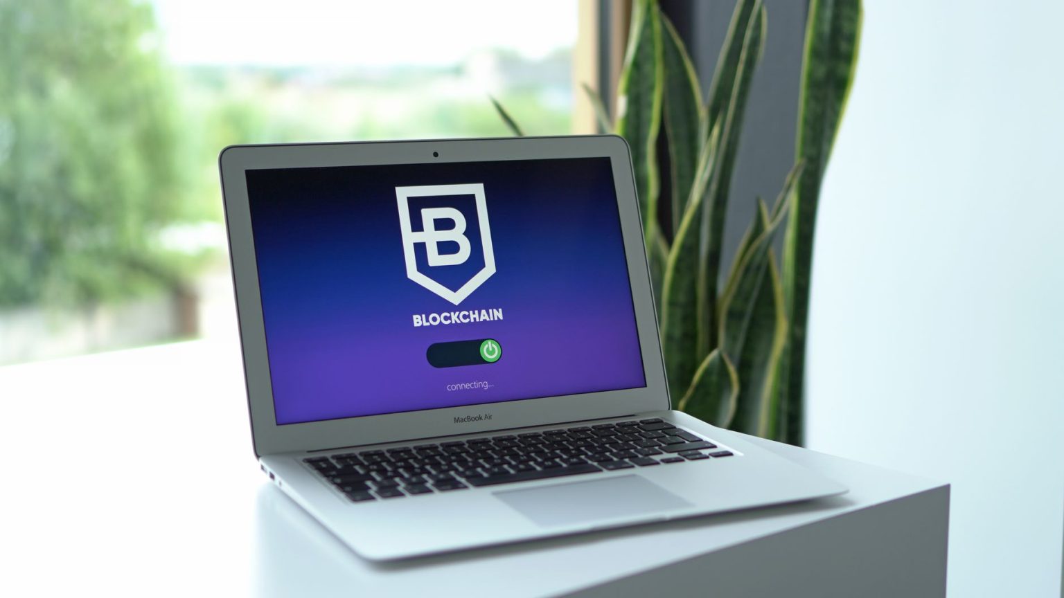 Laptop exibindo uma interface de conexão com blockchain sobre uma mesa, em ambiente interno.